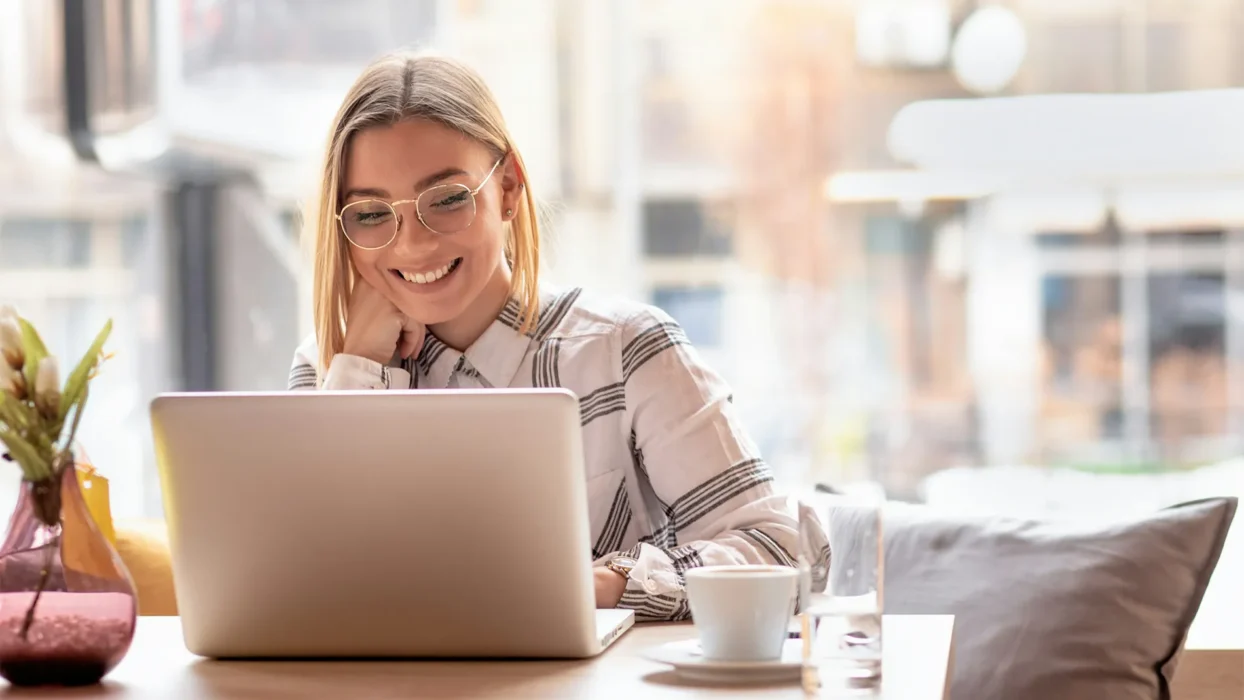 Portrait of young woman using laptop at cafe, she is working on laptop computer at a coffee shop