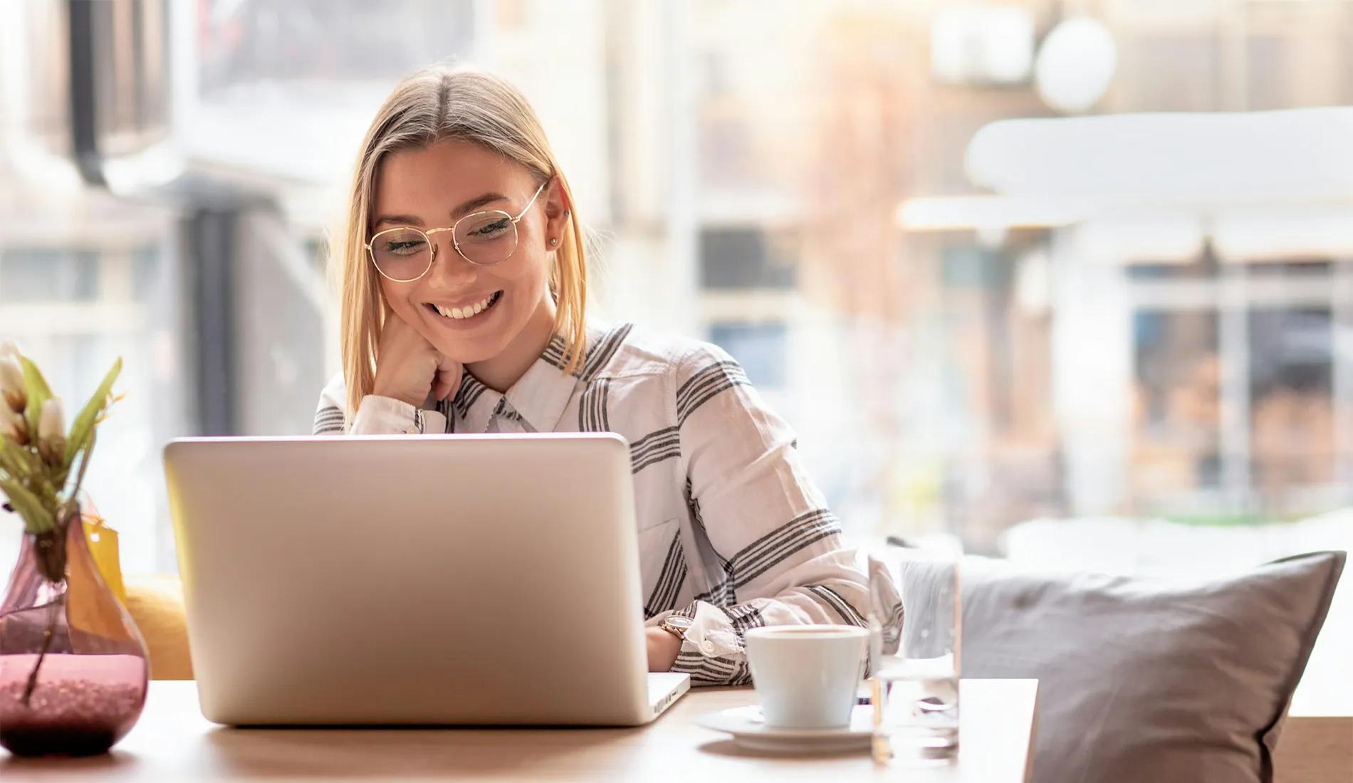 Portrait of young woman using laptop at cafe, she is working on laptop computer at a coffee shop