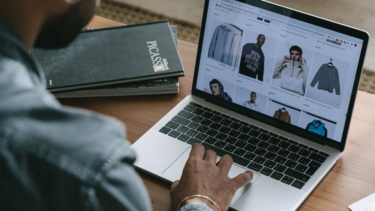 Young man browsing online shopping website on laptop indoors
