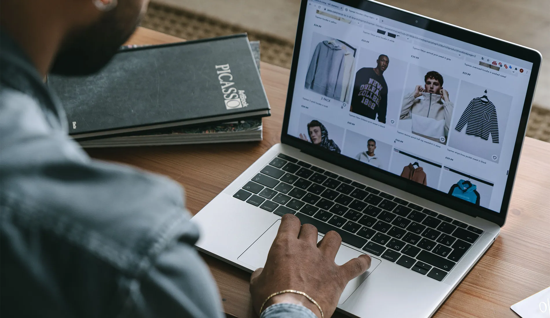 Young man browsing online shopping website on laptop indoors